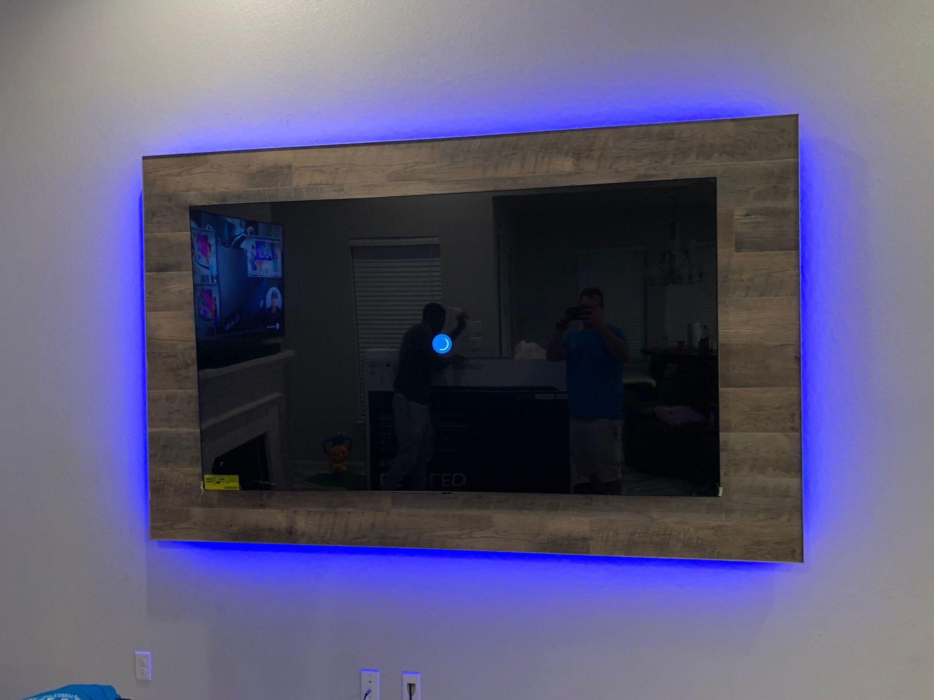 A flat screen tv is mounted on a wall with blue lights around it.