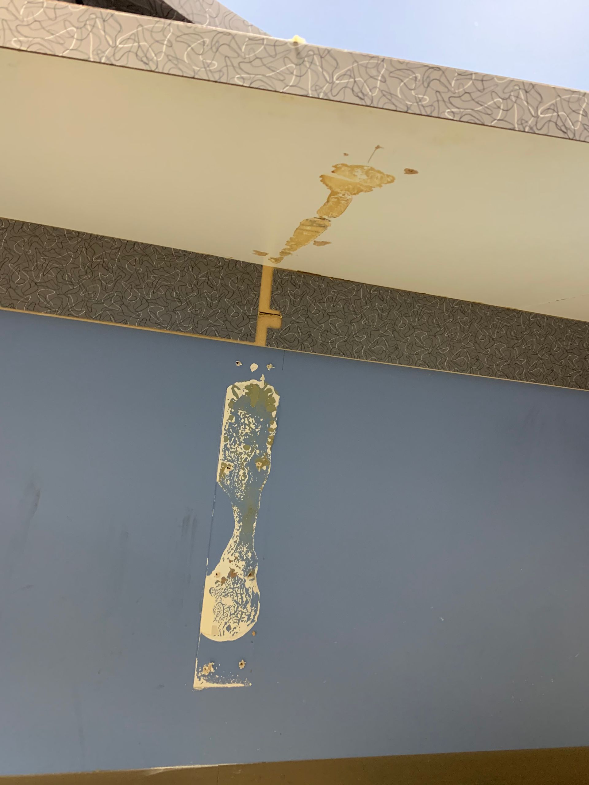 A blue wall with a white ceiling and a hole in it