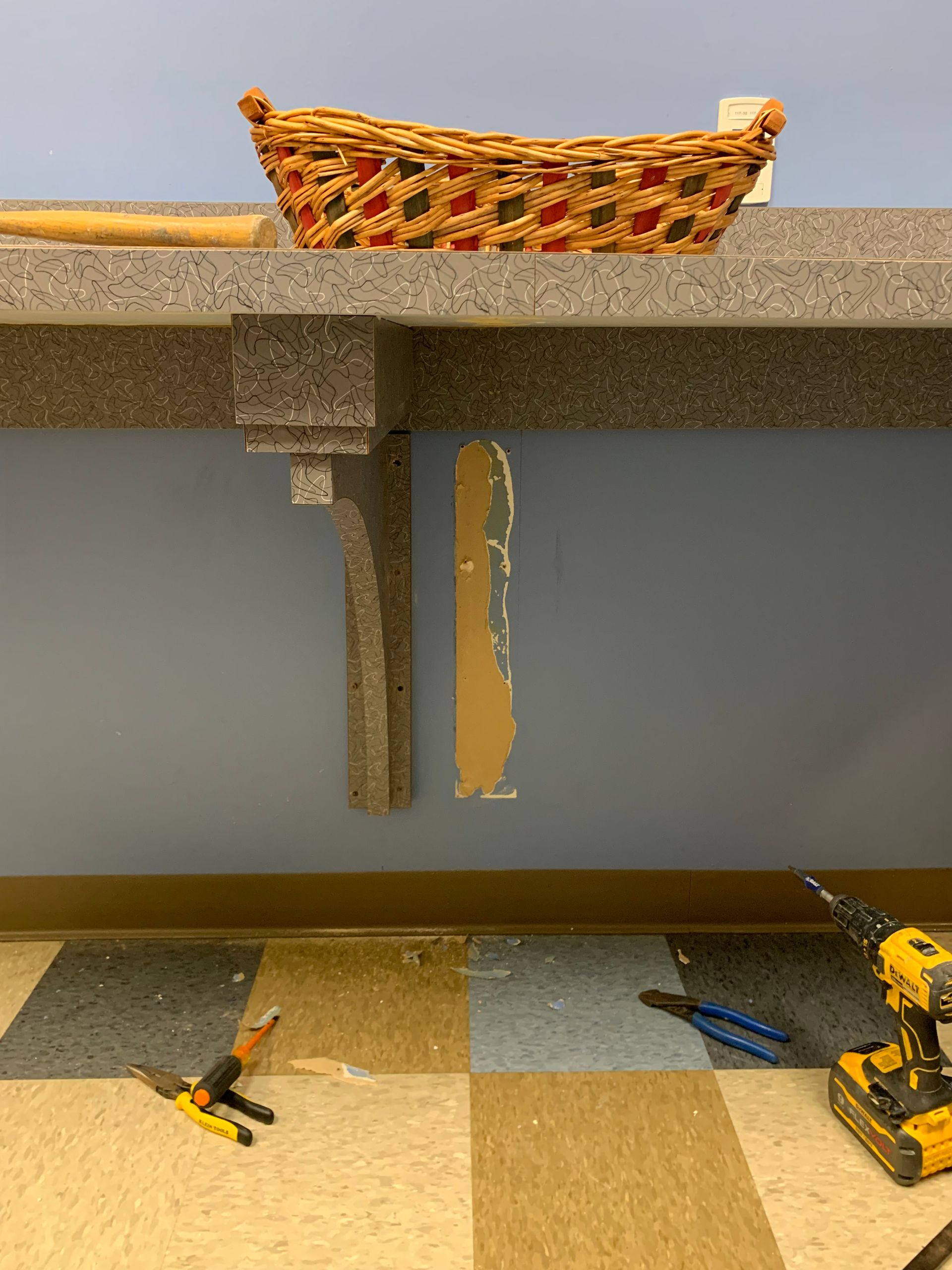 A wicker basket is sitting on top of a counter next to a drill and pliers.