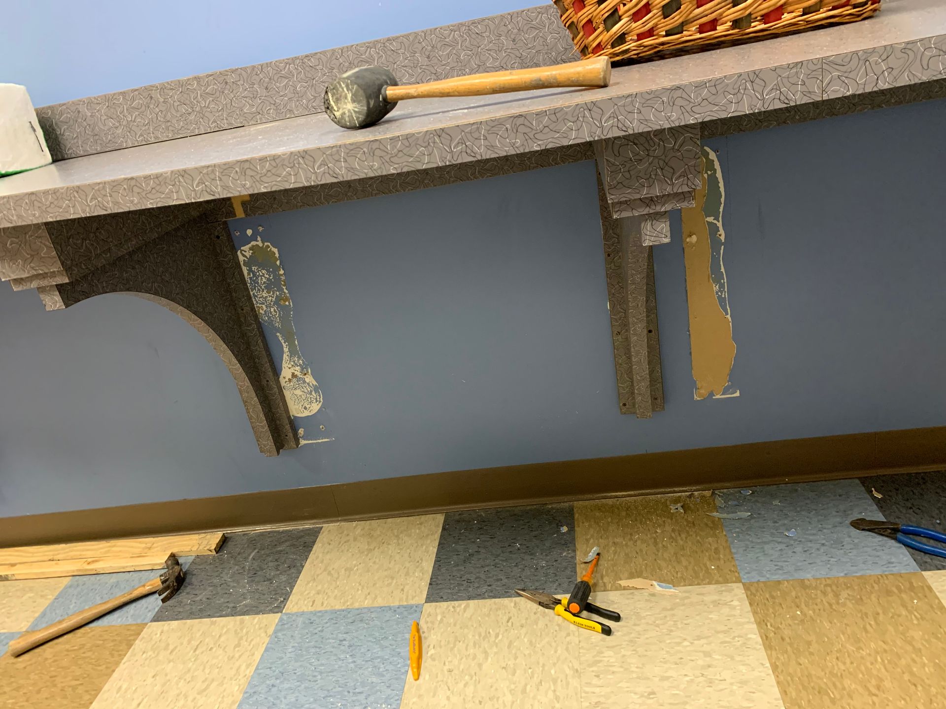 A hammer is sitting on top of a counter next to a basket.