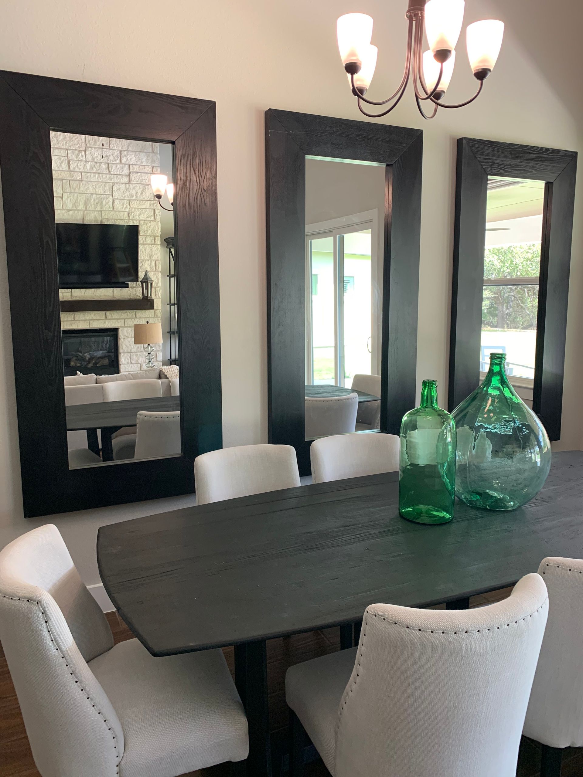 A dining room with a table , chairs , mirrors and a chandelier.