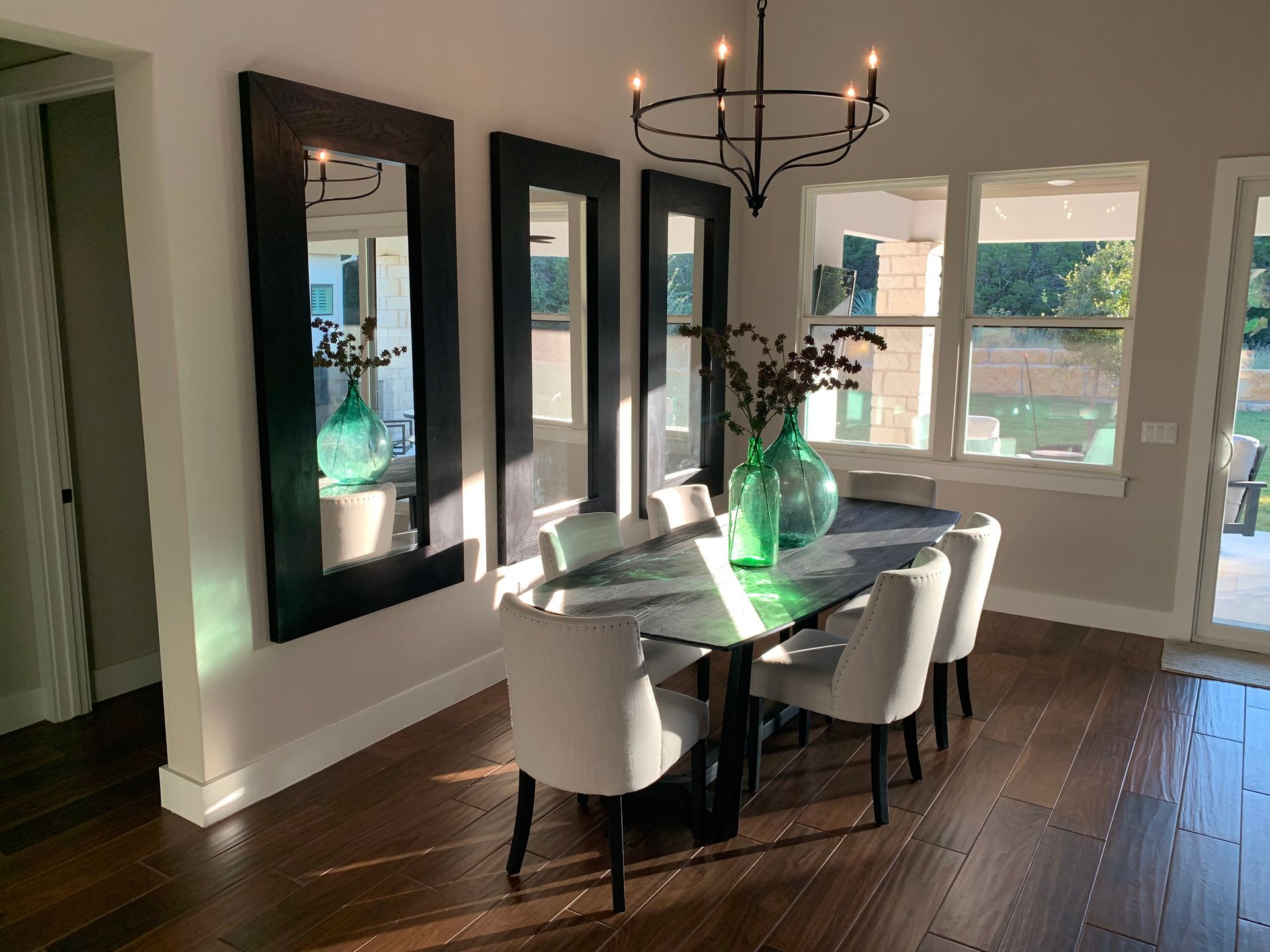 A dining room with a table , chairs , mirrors and a chandelier.