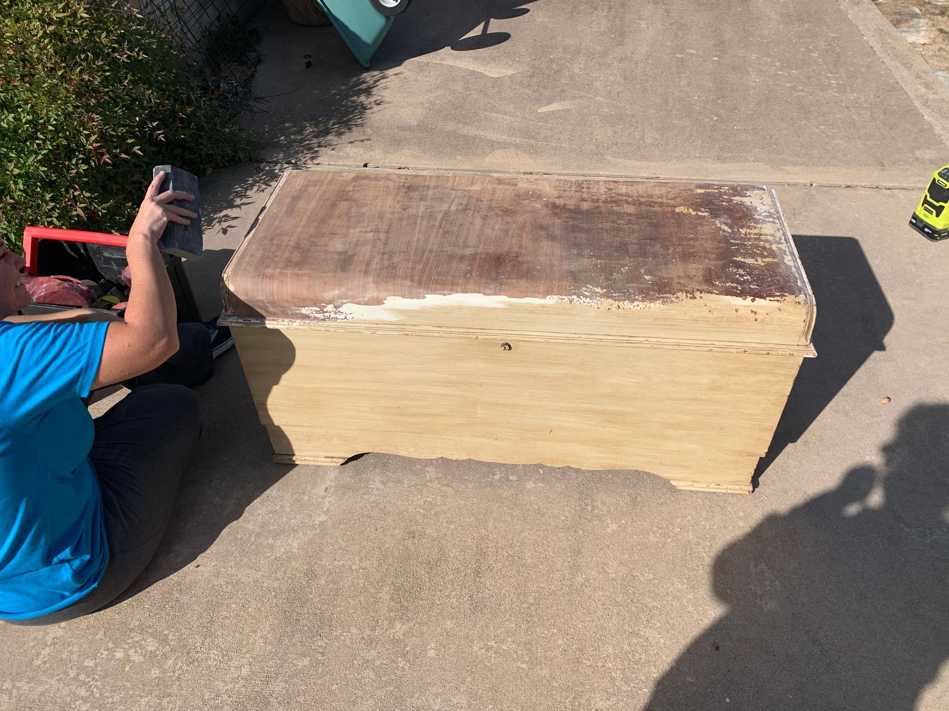 A man is kneeling down next to a large wooden box.