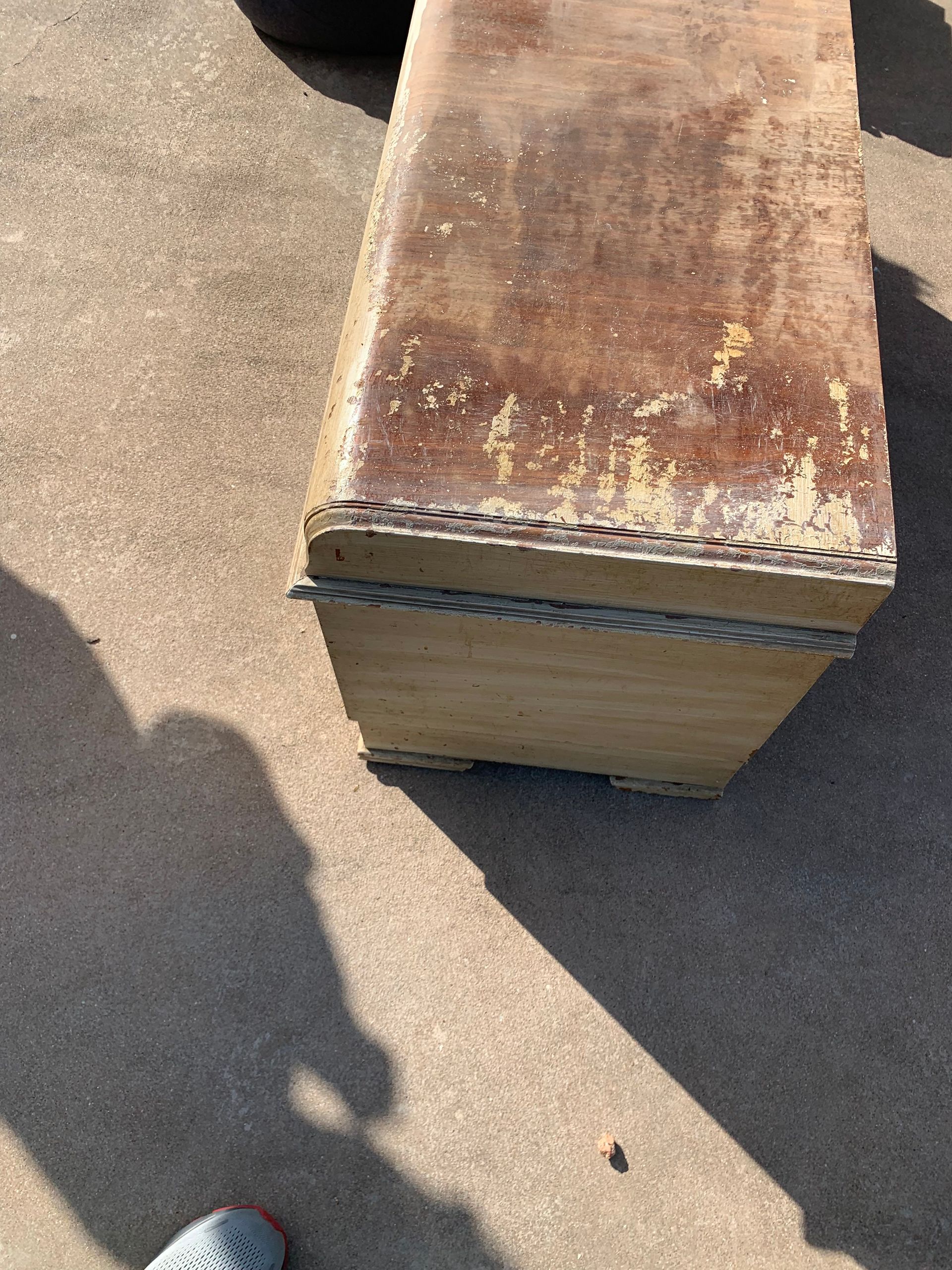 A person is standing next to a wooden box on the ground.