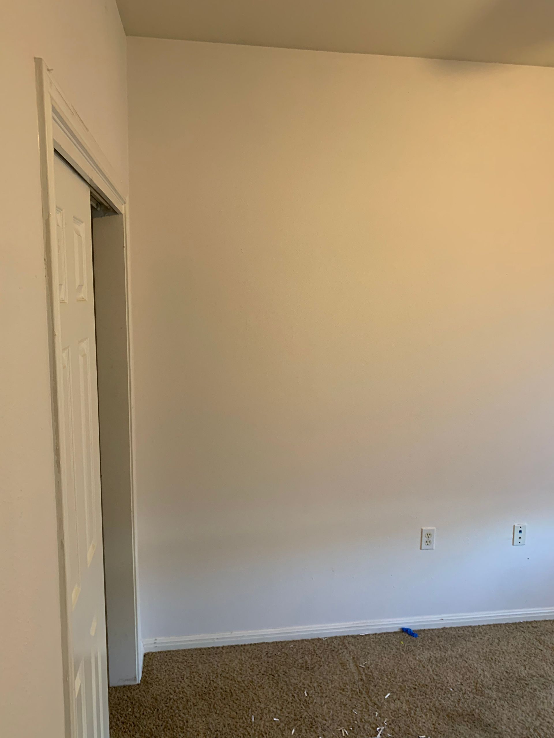 An empty room with white walls and brown carpet.