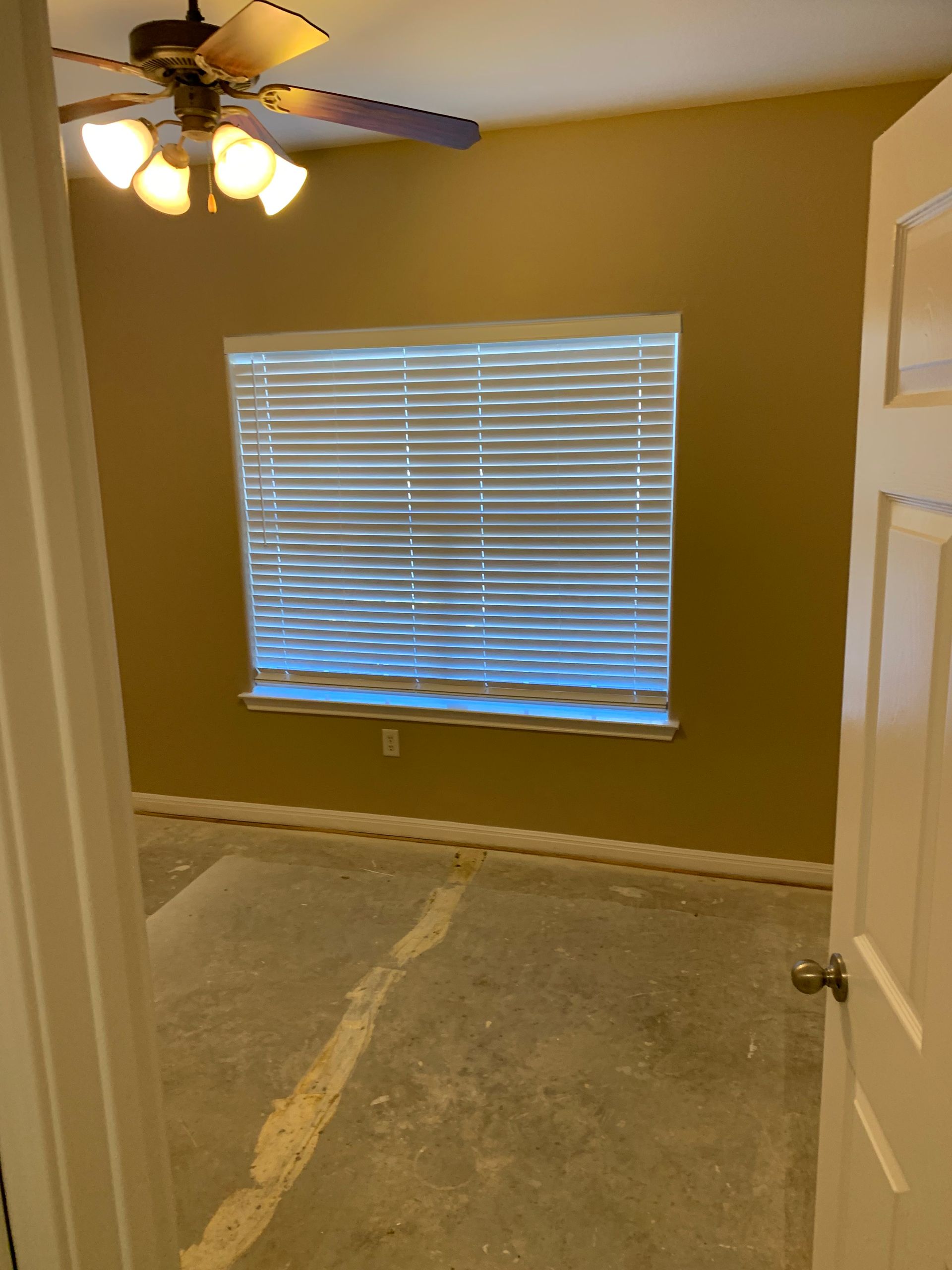 There is a ceiling fan in the room and a window with blinds.