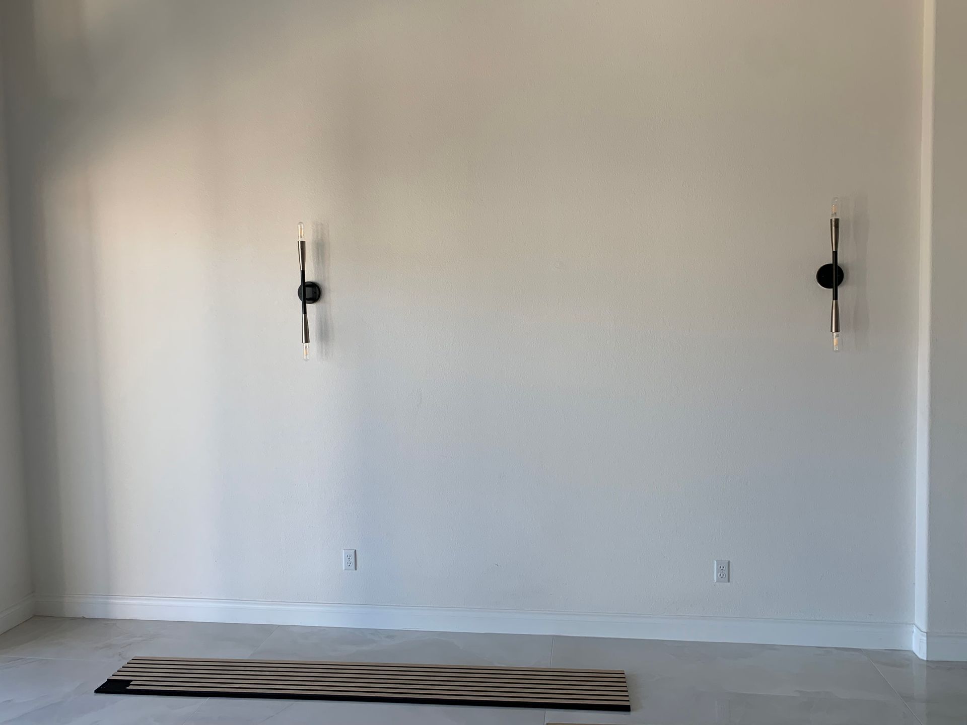 An empty room with two lights on the wall and a rug on the floor.