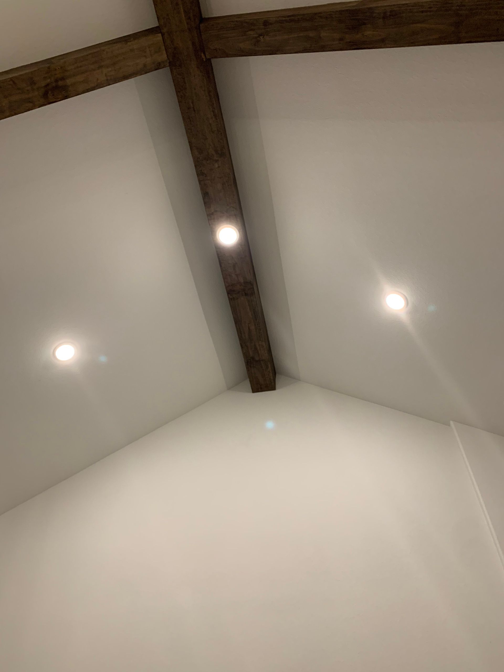 A room with a white ceiling and wooden beams.