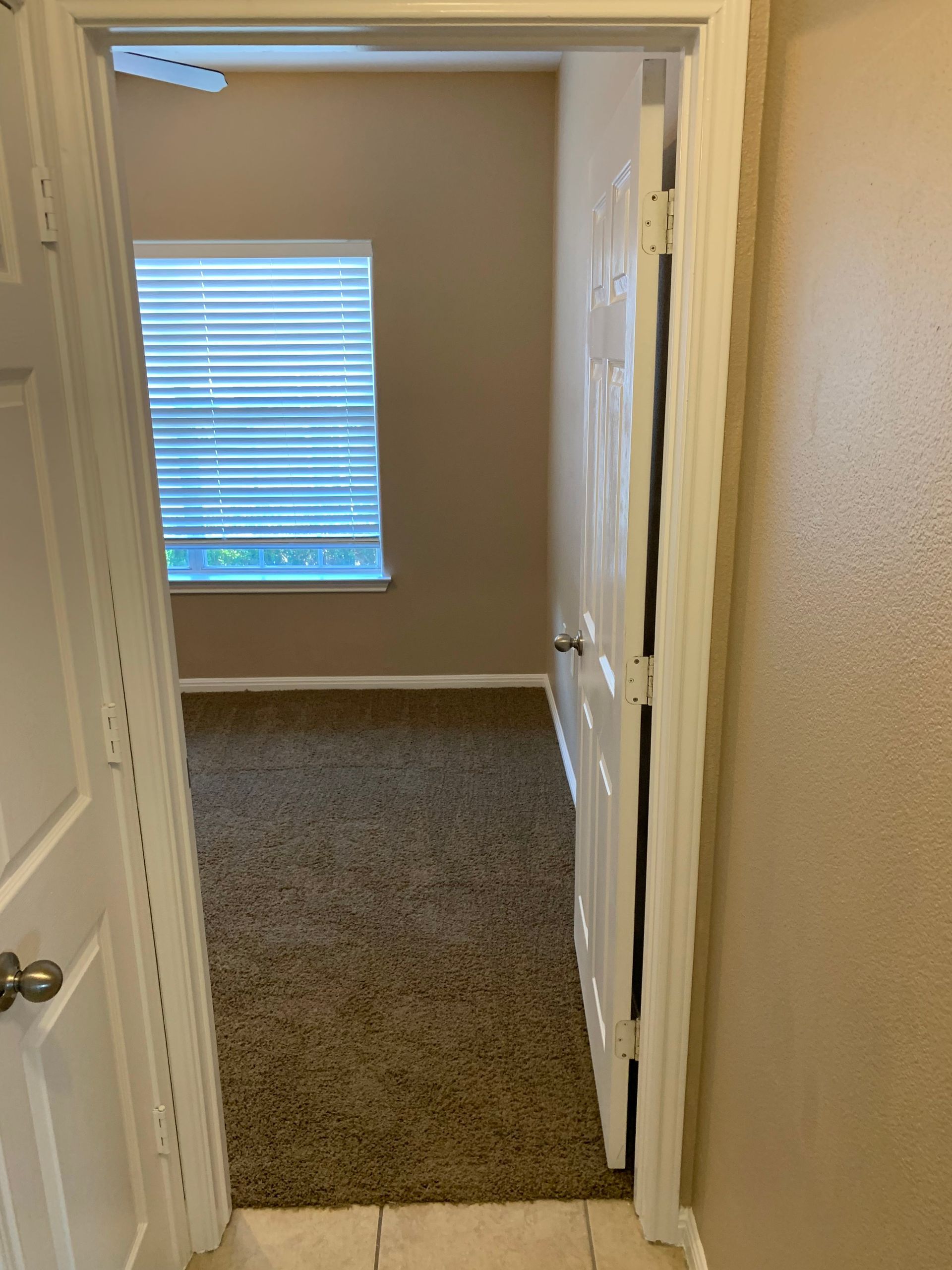 A doorway leading to an empty bedroom with a window.