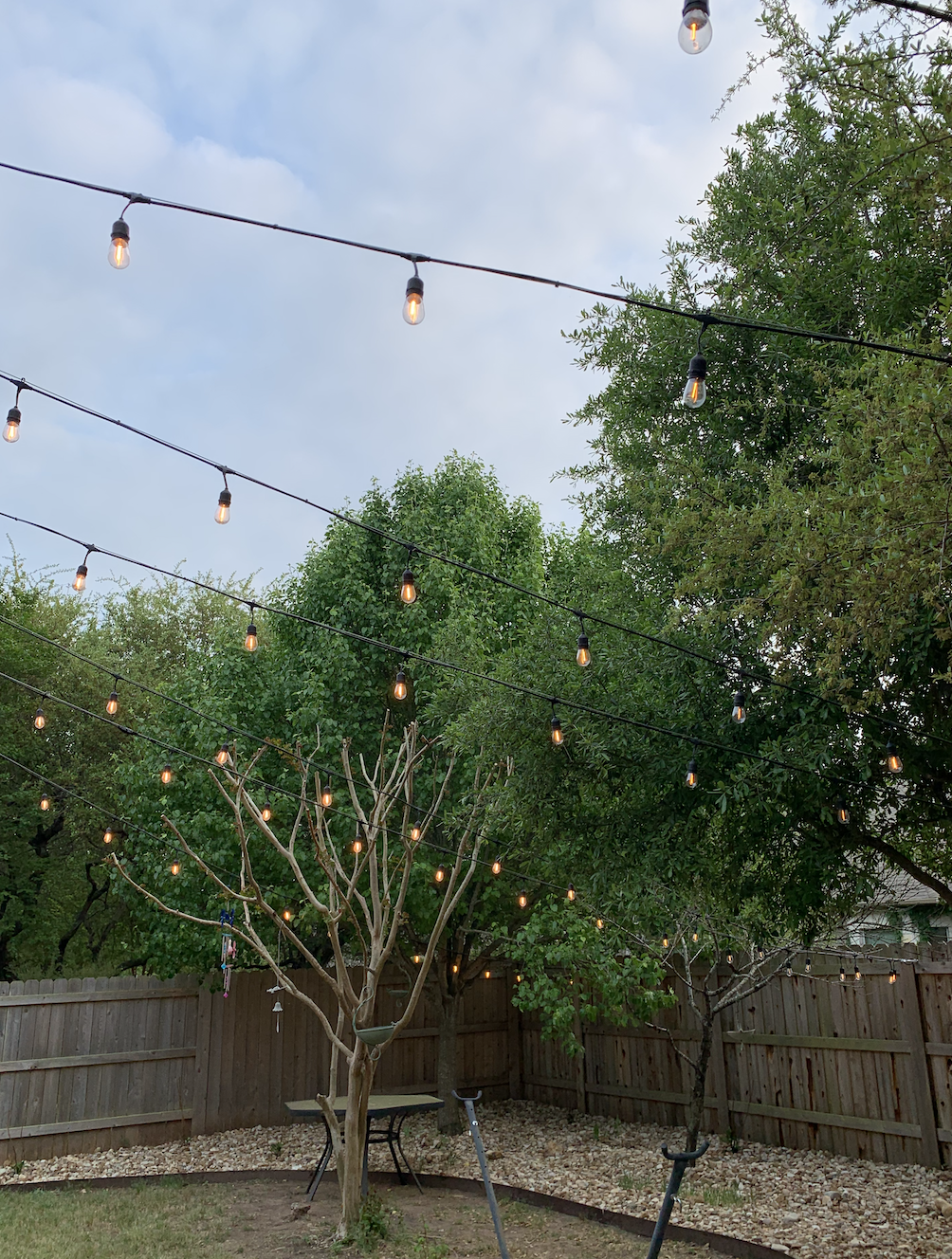 A backyard with a picnic table and a tree with string lights hanging from it.