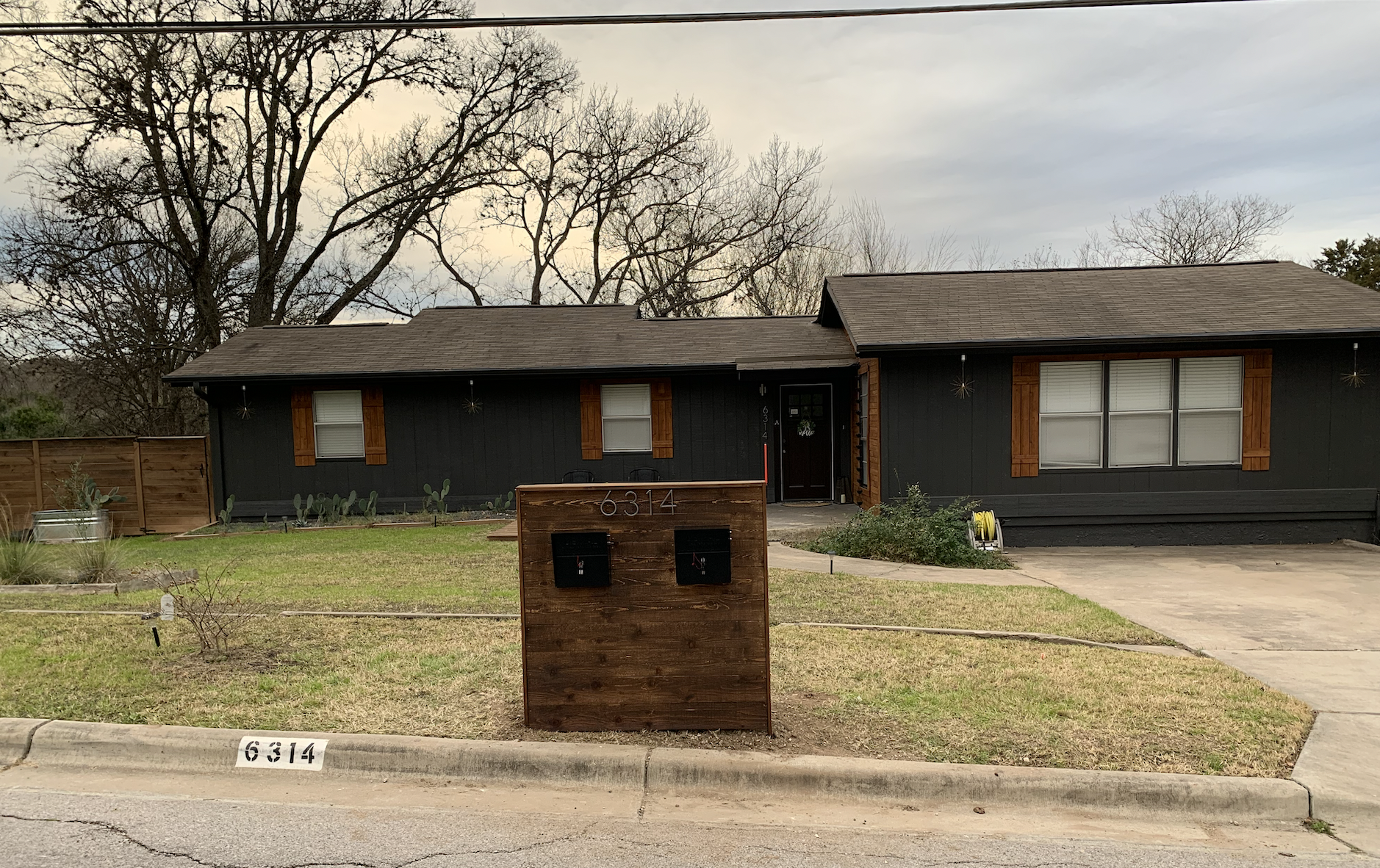 A black house with a brick mailbox in front of it.