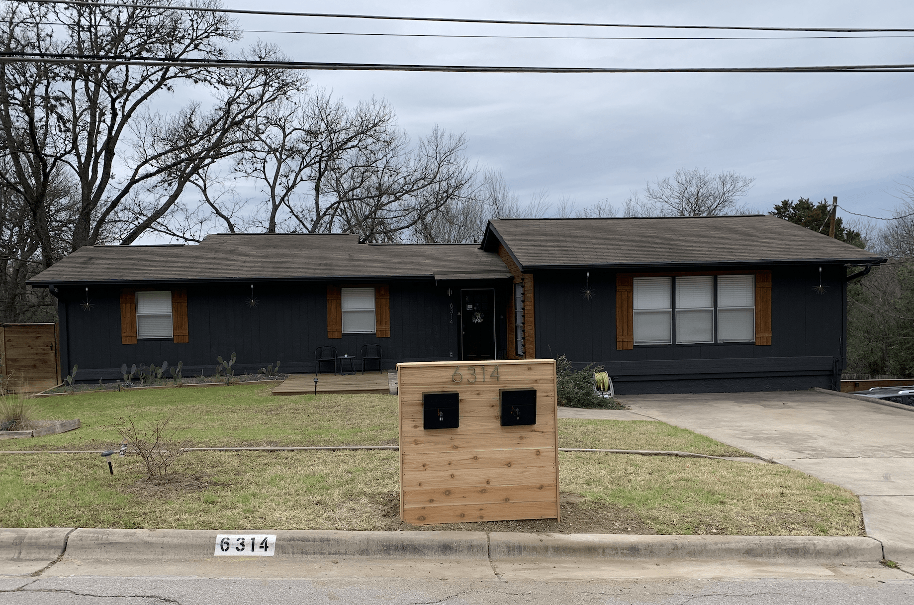A black house with a wooden mailbox in front of it.