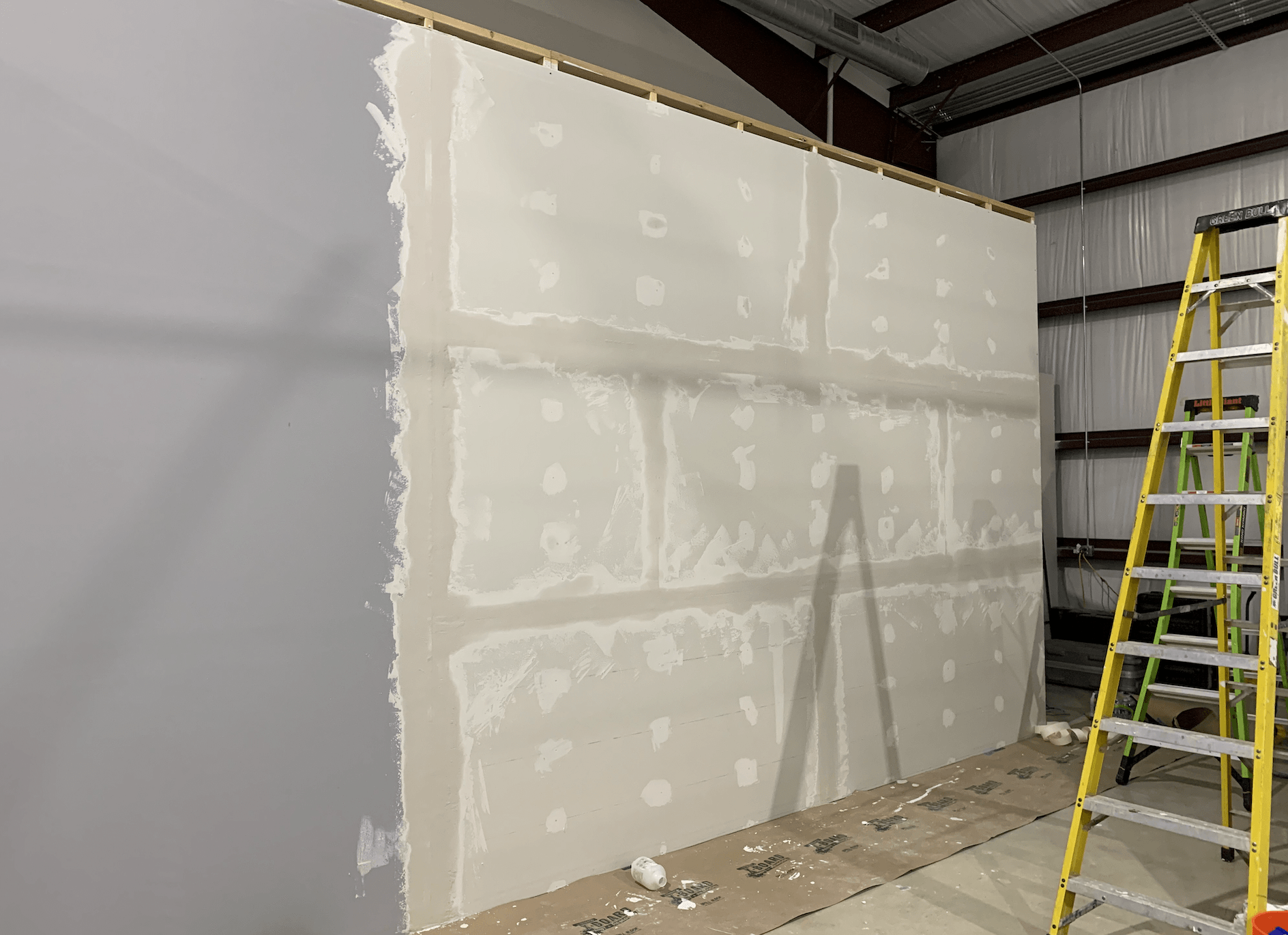 A ladder is sitting next to a wall that is being painted.