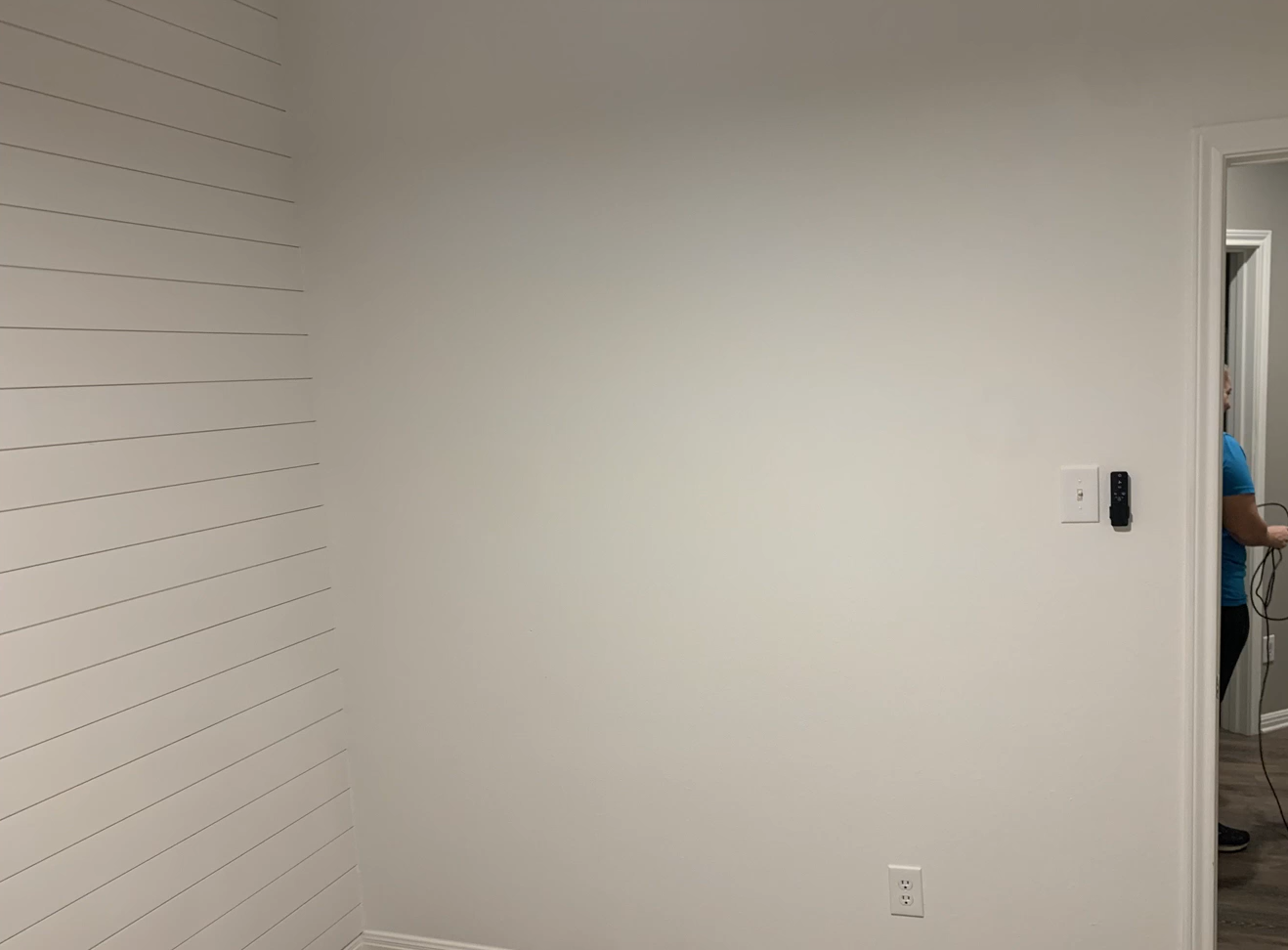 A man is painting the ceiling of a room with a roller.