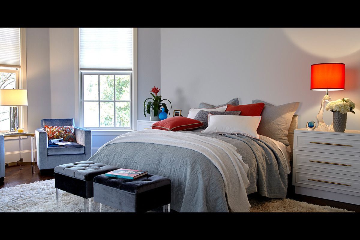 A bedroom with a bed a chair and a lamp