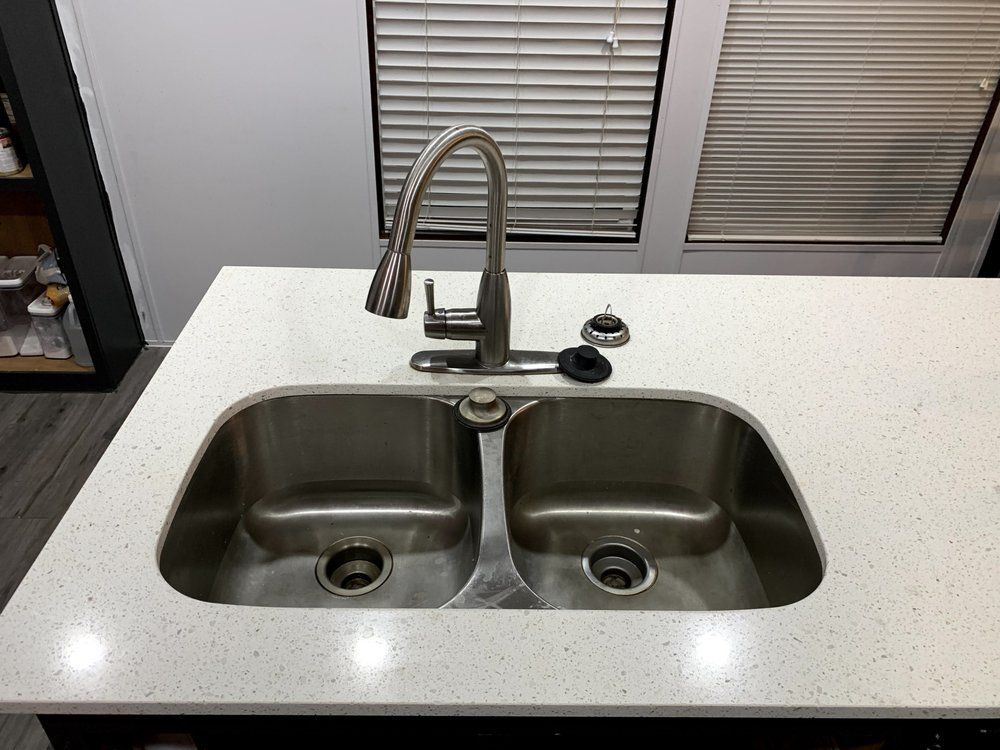A kitchen sink with two sinks and a faucet on a white counter top.