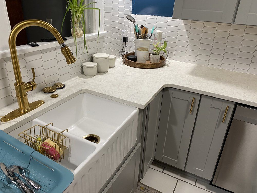 A kitchen with a white sink and a gold faucet.