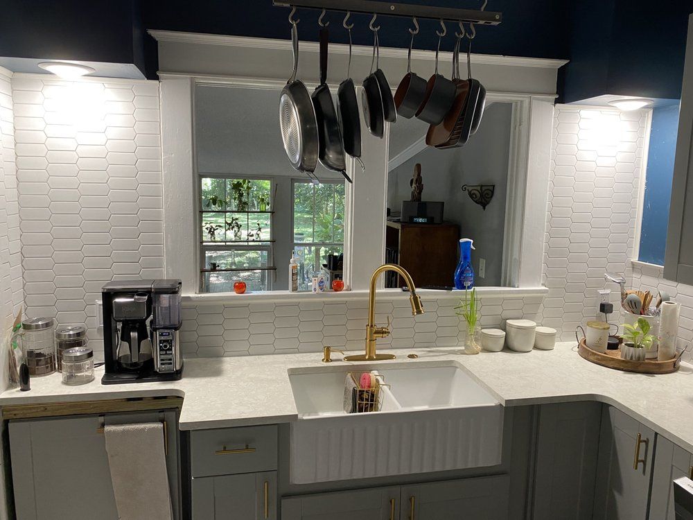 A kitchen with a sink and pots and pans hanging from the ceiling.