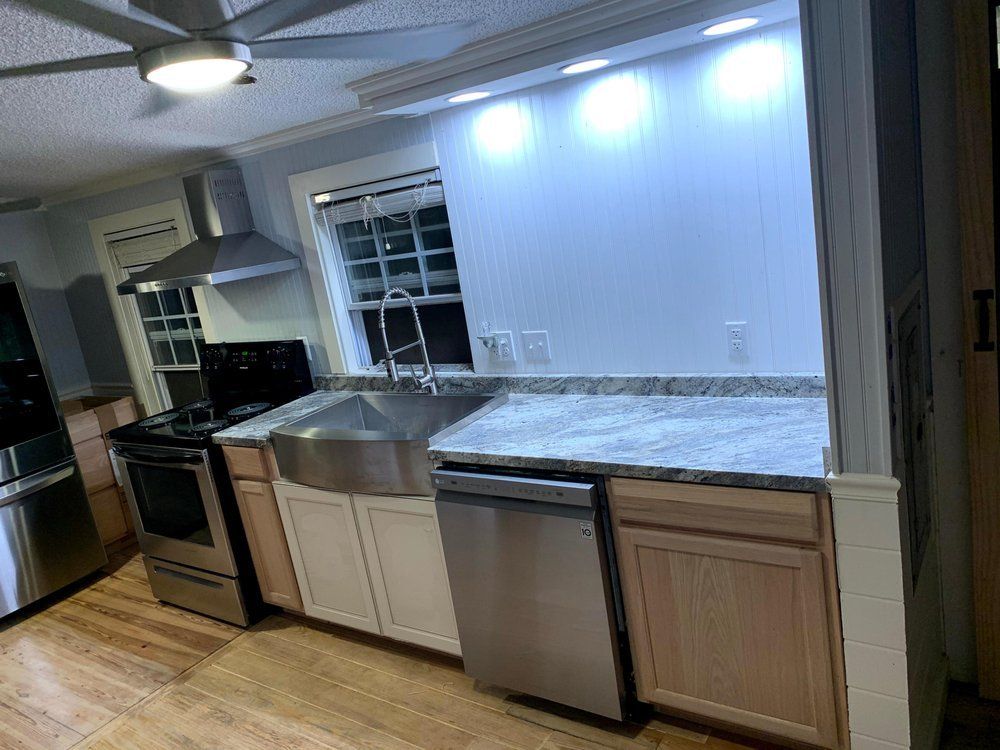 A kitchen with a sink , stove , dishwasher and ceiling fan.