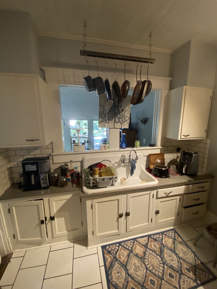 A kitchen with white cabinets , a sink , and a rug.