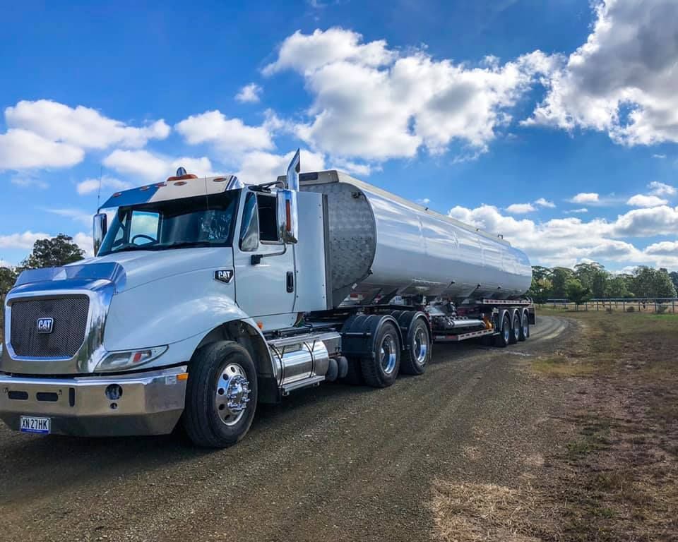 White Tanker Truck on A Dirt Road Under a Blue Sky with Clouds — Highlands Water Cartage in Glenquarry, NSW