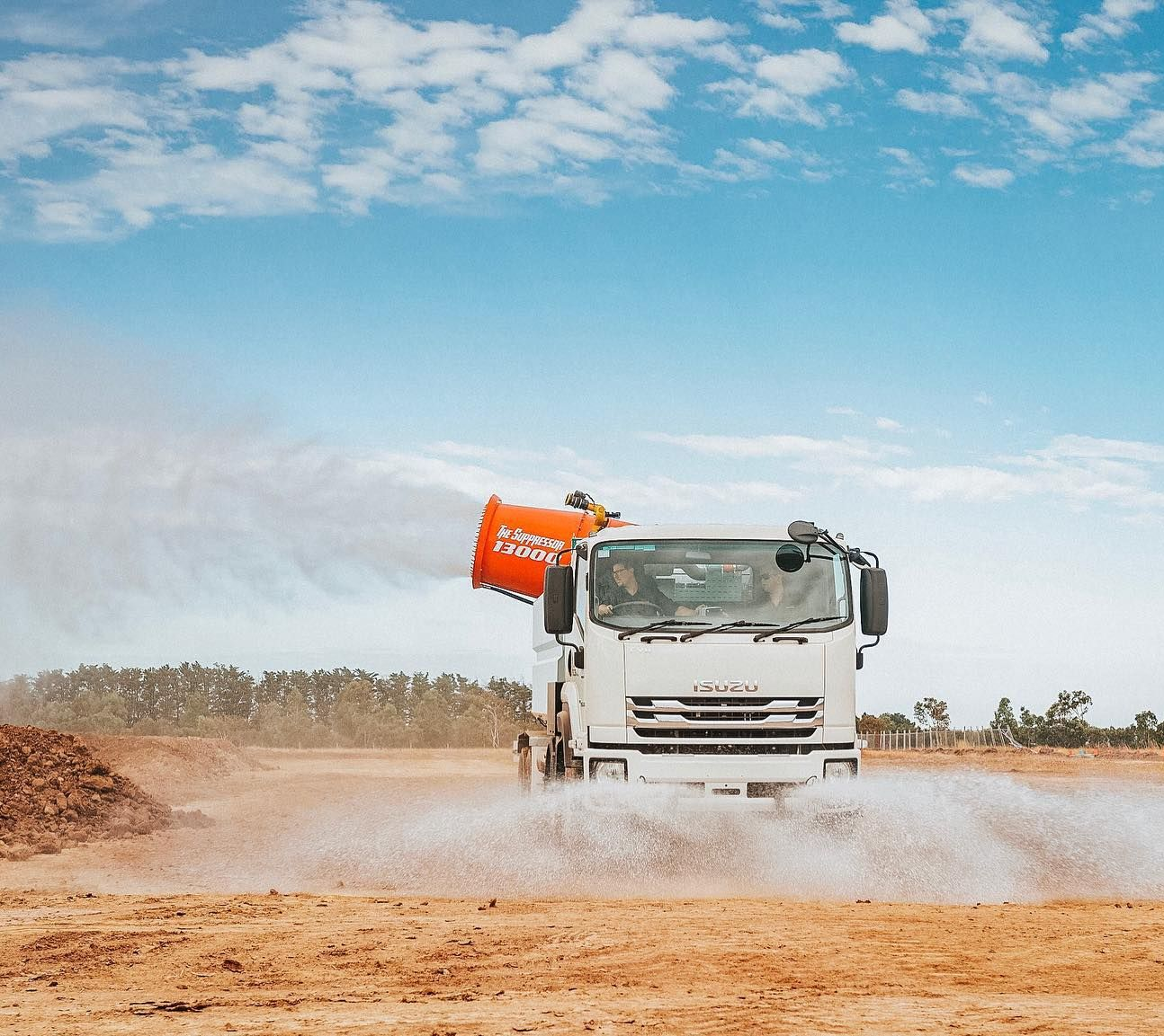 Dust suppression truck spraying water on a dusty field under a blue sky — Highlands Water Cartage in Glenquarry, NSW