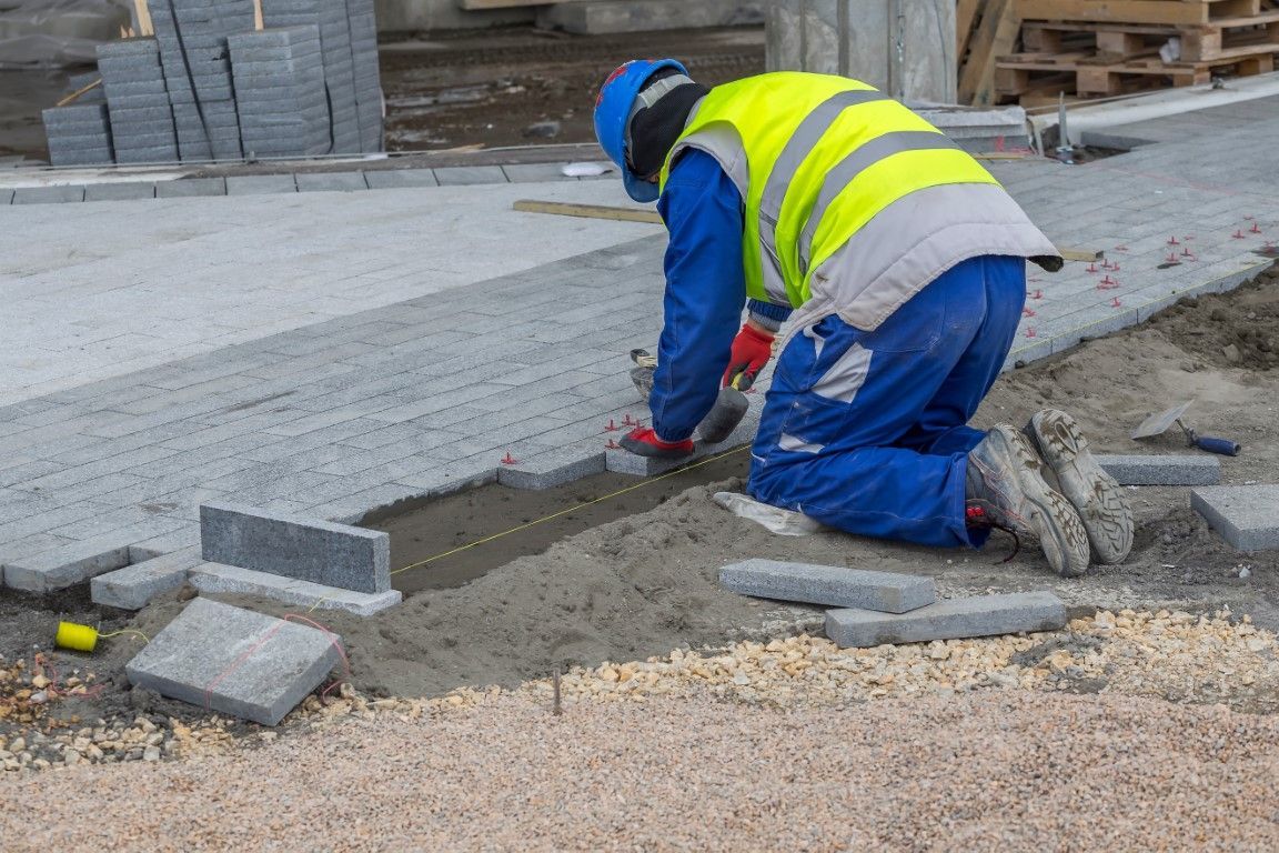 Photo of installer laying paver bricks down over base layer sand.