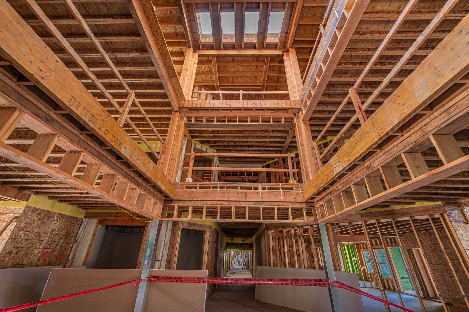 Interior of a wooden building under construction, with exposed beams and open central skylight.