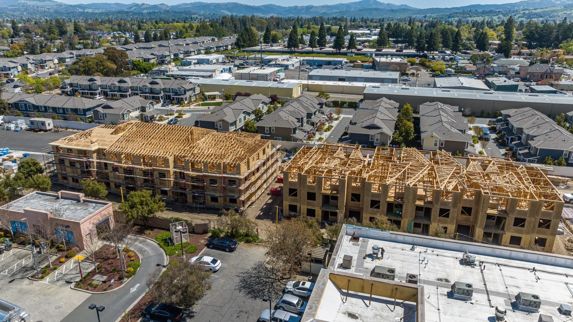 Aerial view of two large, multi-story apartment buildings under construction in a suburban neighborhood.