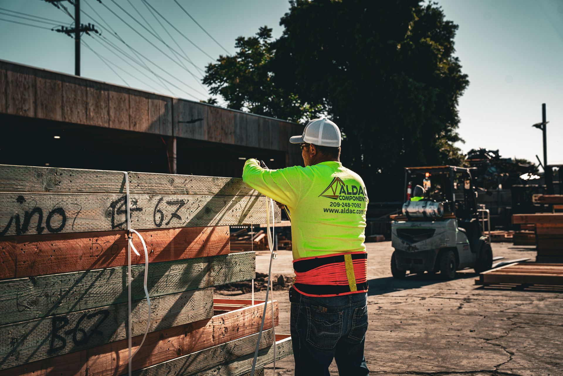 Construction worker in neon safety vest directing a forklift at a roadwork site
