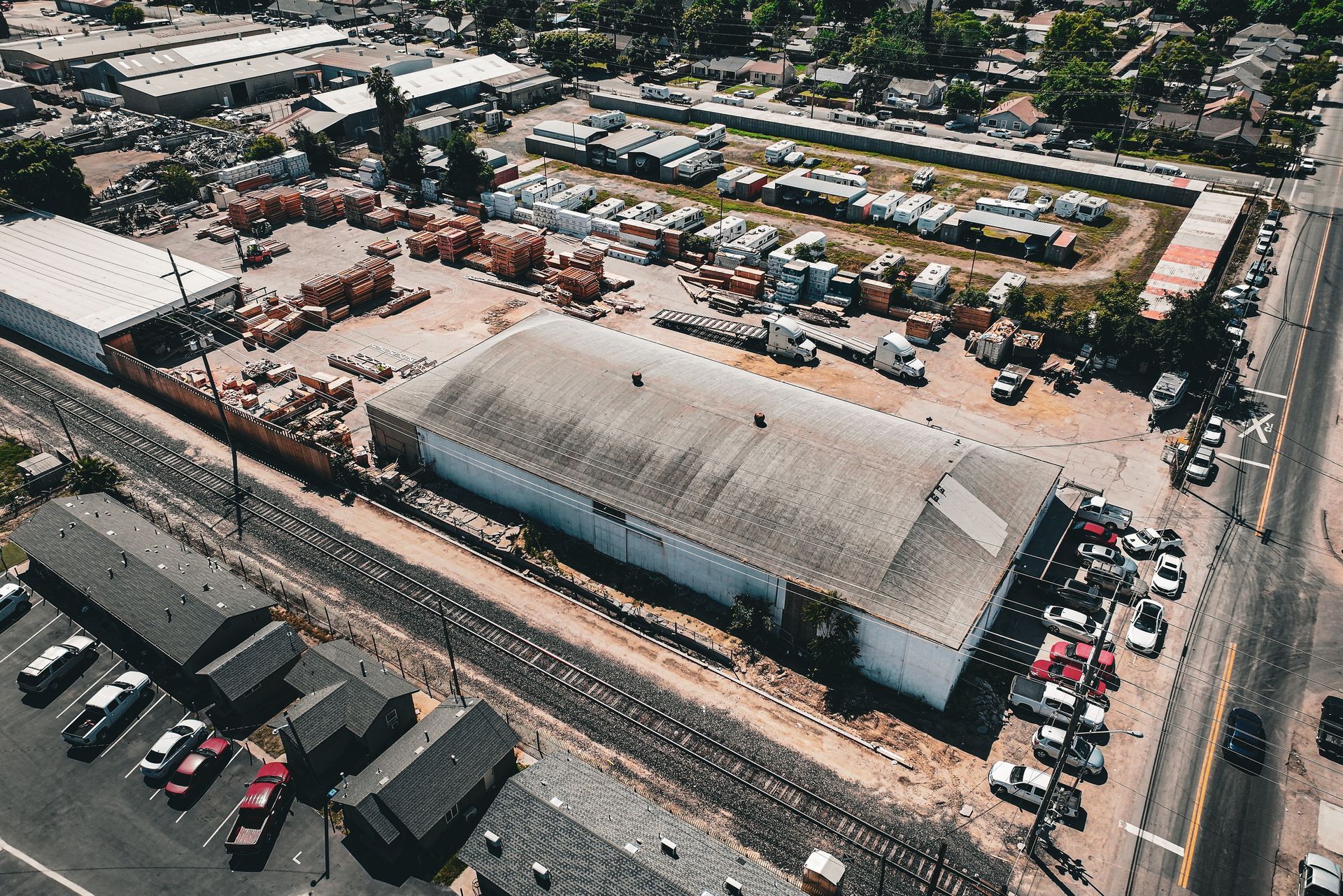 Aerial view of a large industrial building and surrounding parking lot in a commercial area.