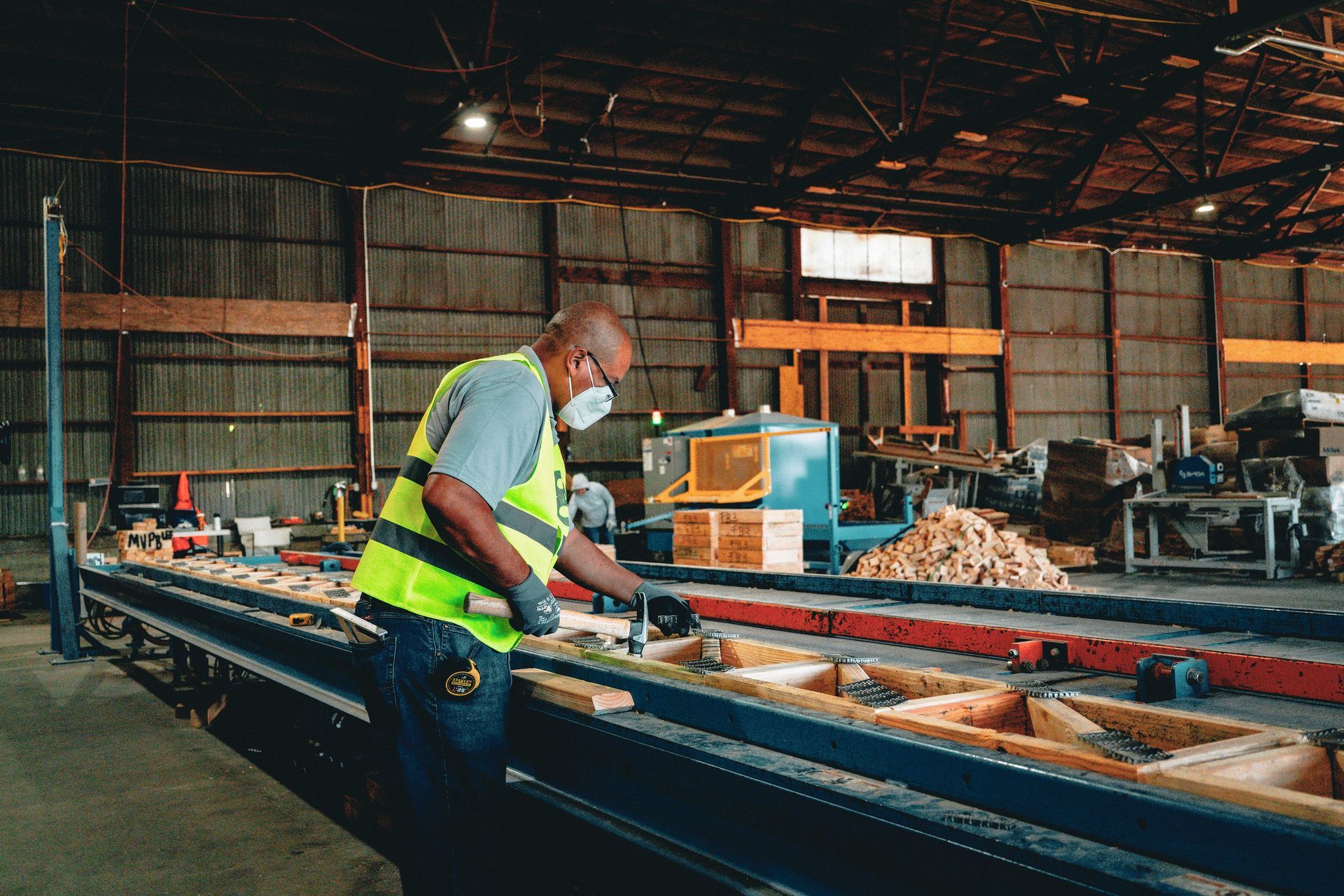 Worker in a high-visibility vest operating machinery in a warehouse workshop