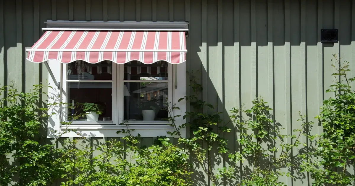 Exterior of a house window with a red and white striped awning, for house awning consultation servic