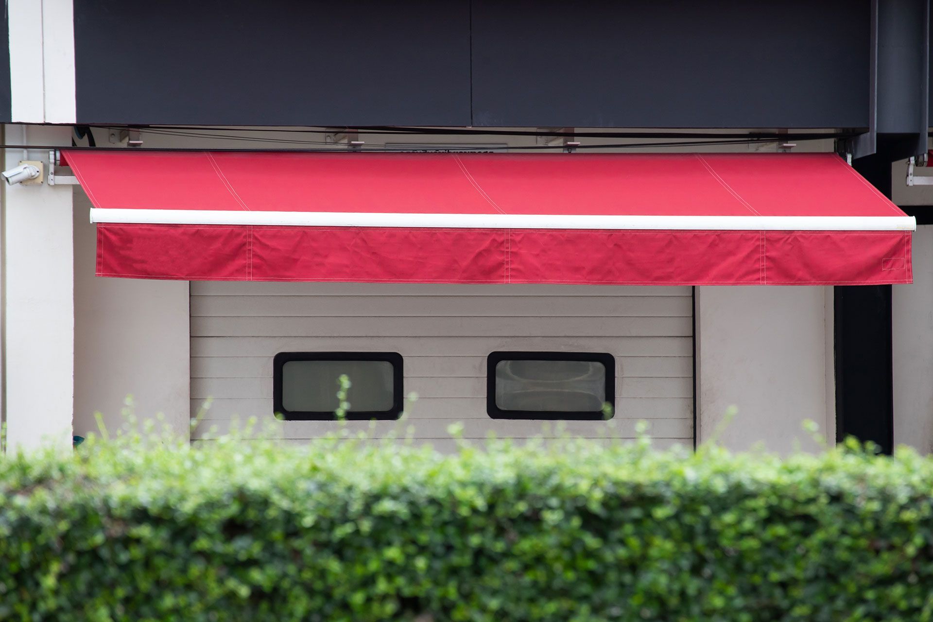 Red retractable awning shading a building façade