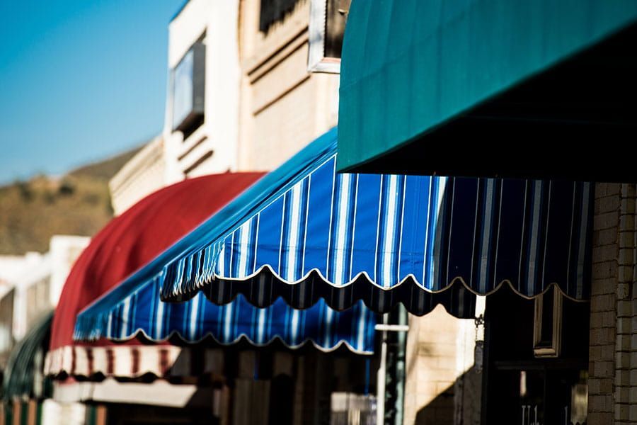 Residential fabric awnings providing shade above building windows.