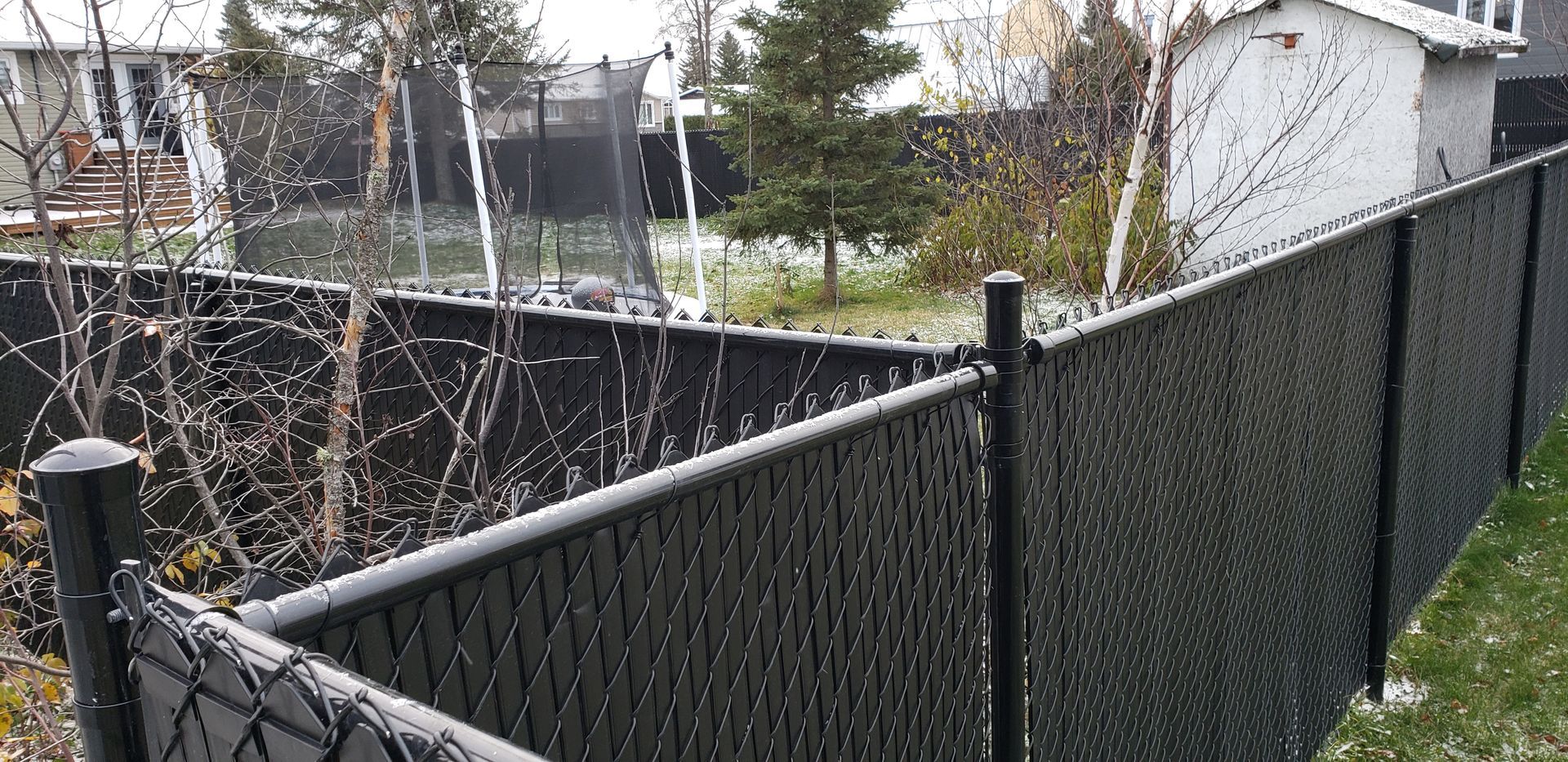 Une clôture grillagée noire se trouve dans l'arrière-cour d'une maison.