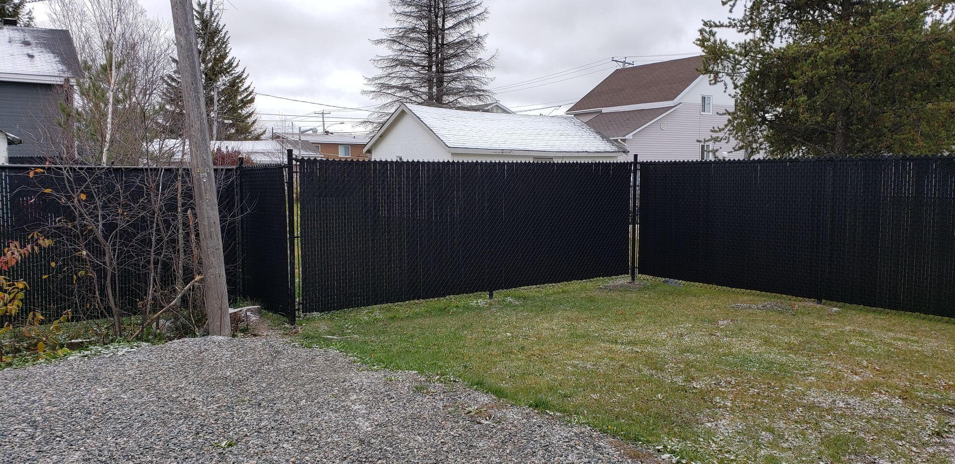 Une clôture à mailles noires entoure une cour verdoyante.