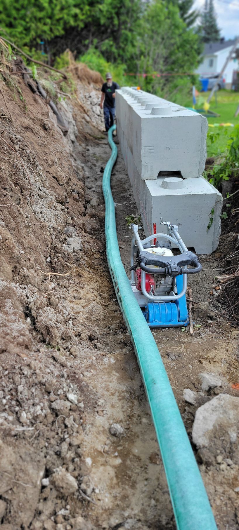 Un homme se tient à côté d'un tuyau vert dans la terre.