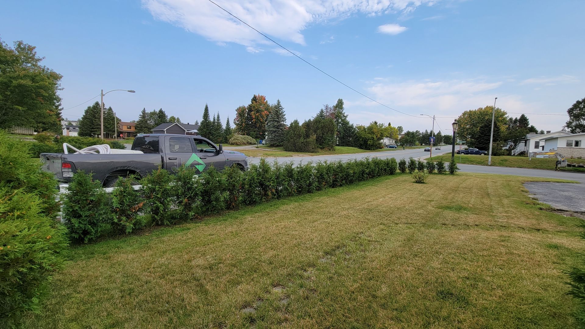 Un camion est garé dans l'herbe à côté d'une haie.