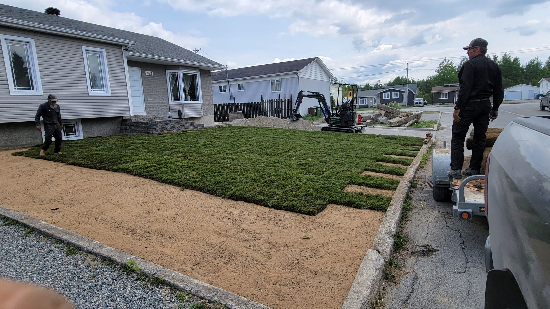 Un homme se tient debout sur une remorque devant une maison.