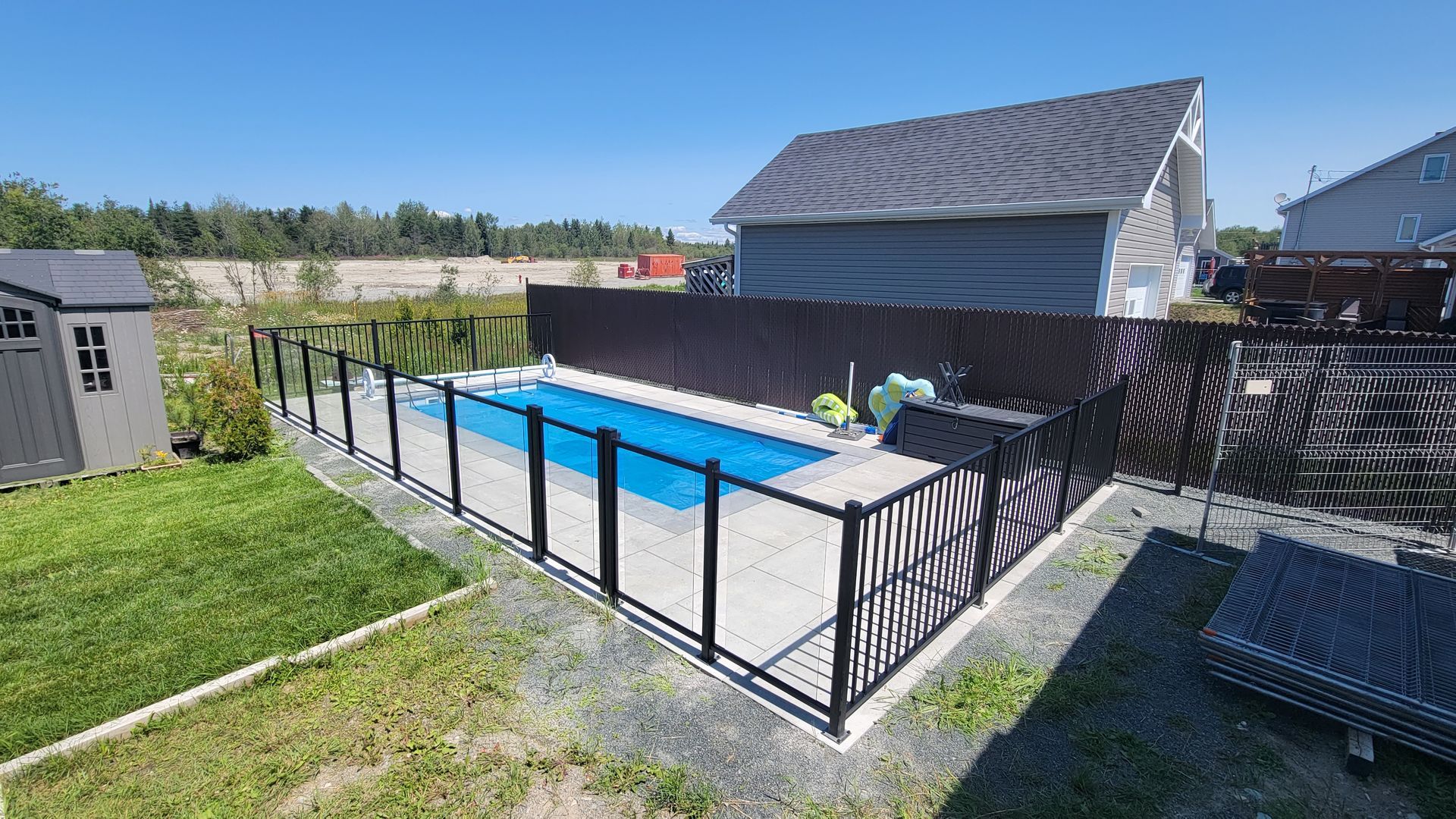 Une grande piscine est entourée d'une clôture dans une cour arrière.