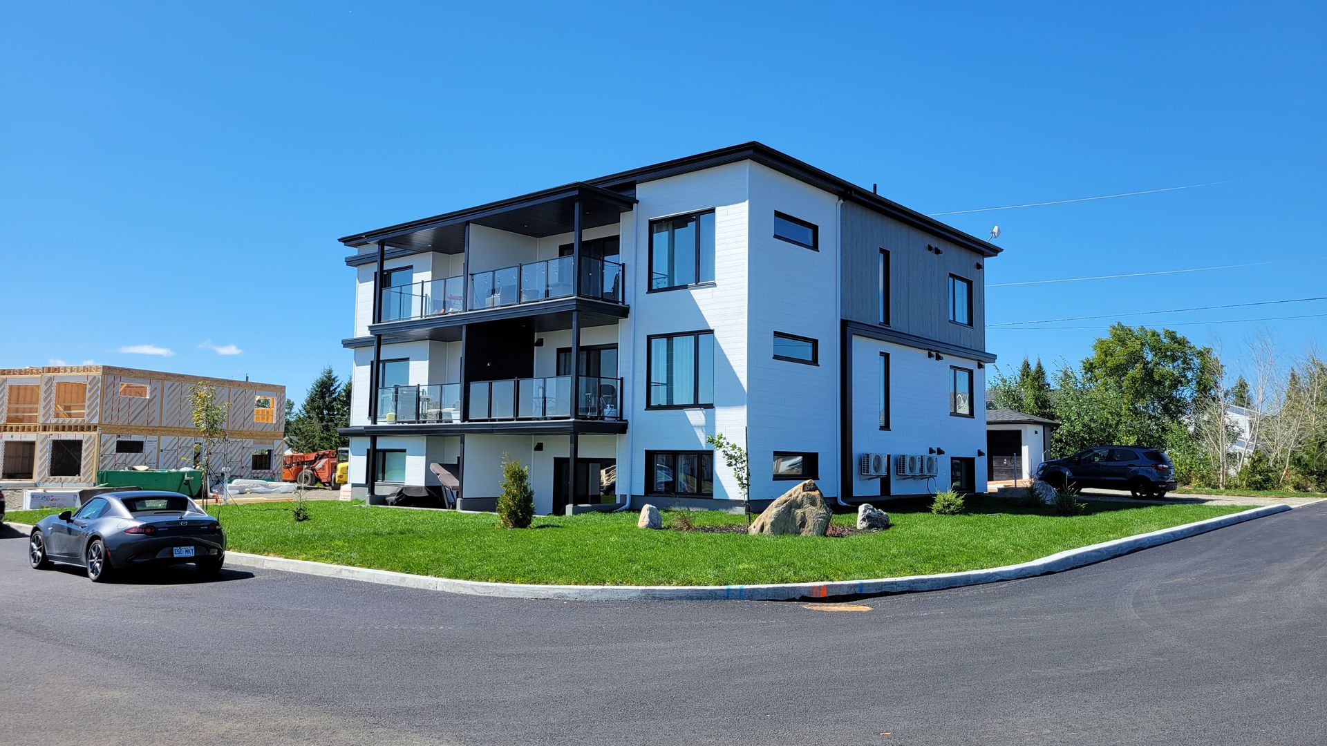 Un grand bâtiment blanc avec beaucoup de fenêtres se trouve au coin d'une rue.