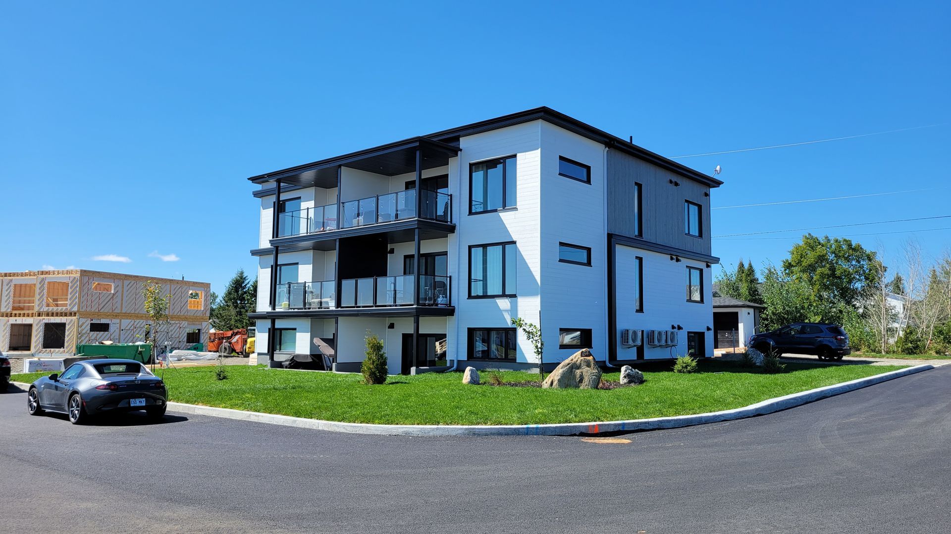 Un grand immeuble d'appartements avec des voitures garées devant.