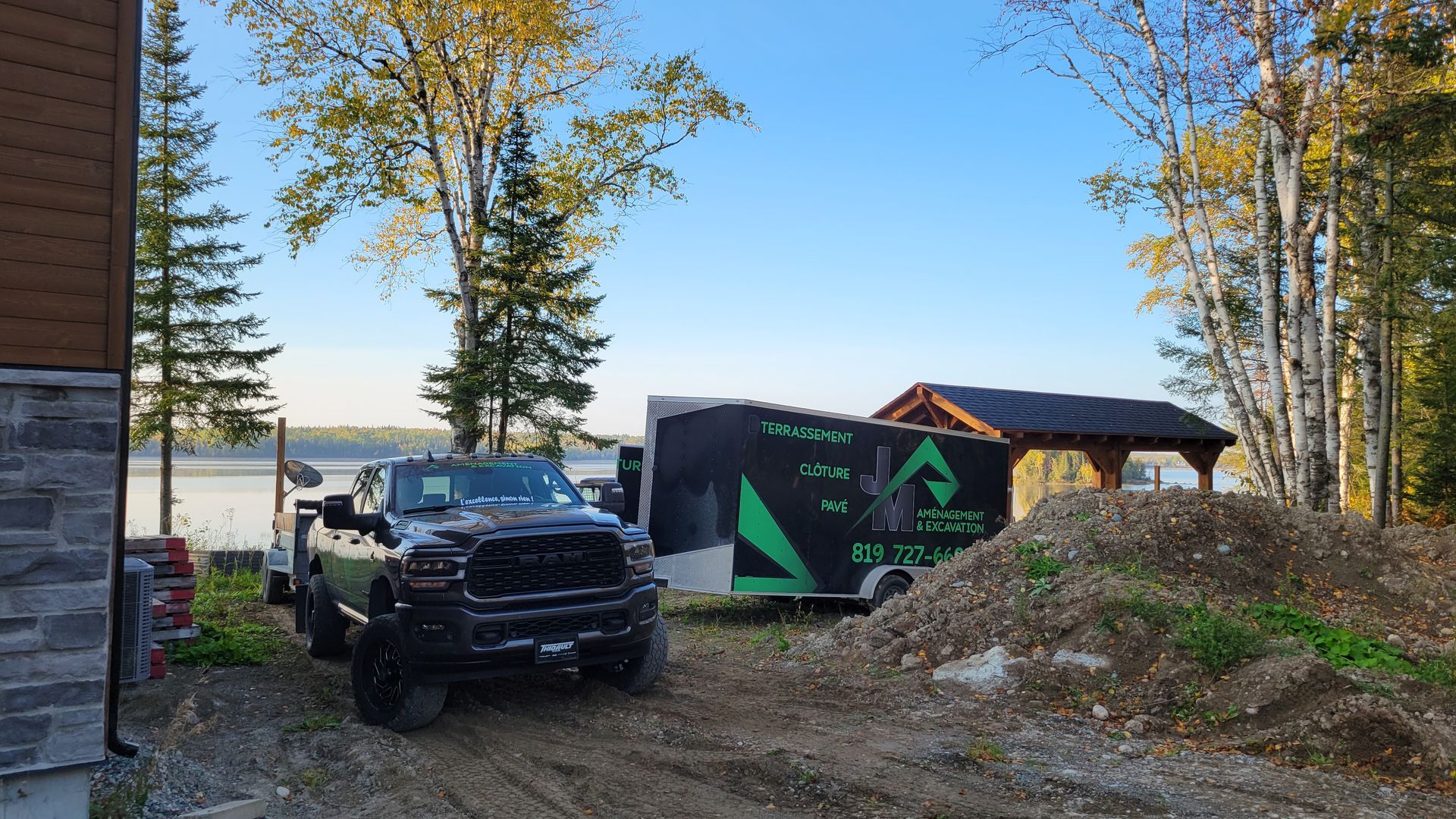 Un camion est garé devant une maison à côté d'une remorque.
