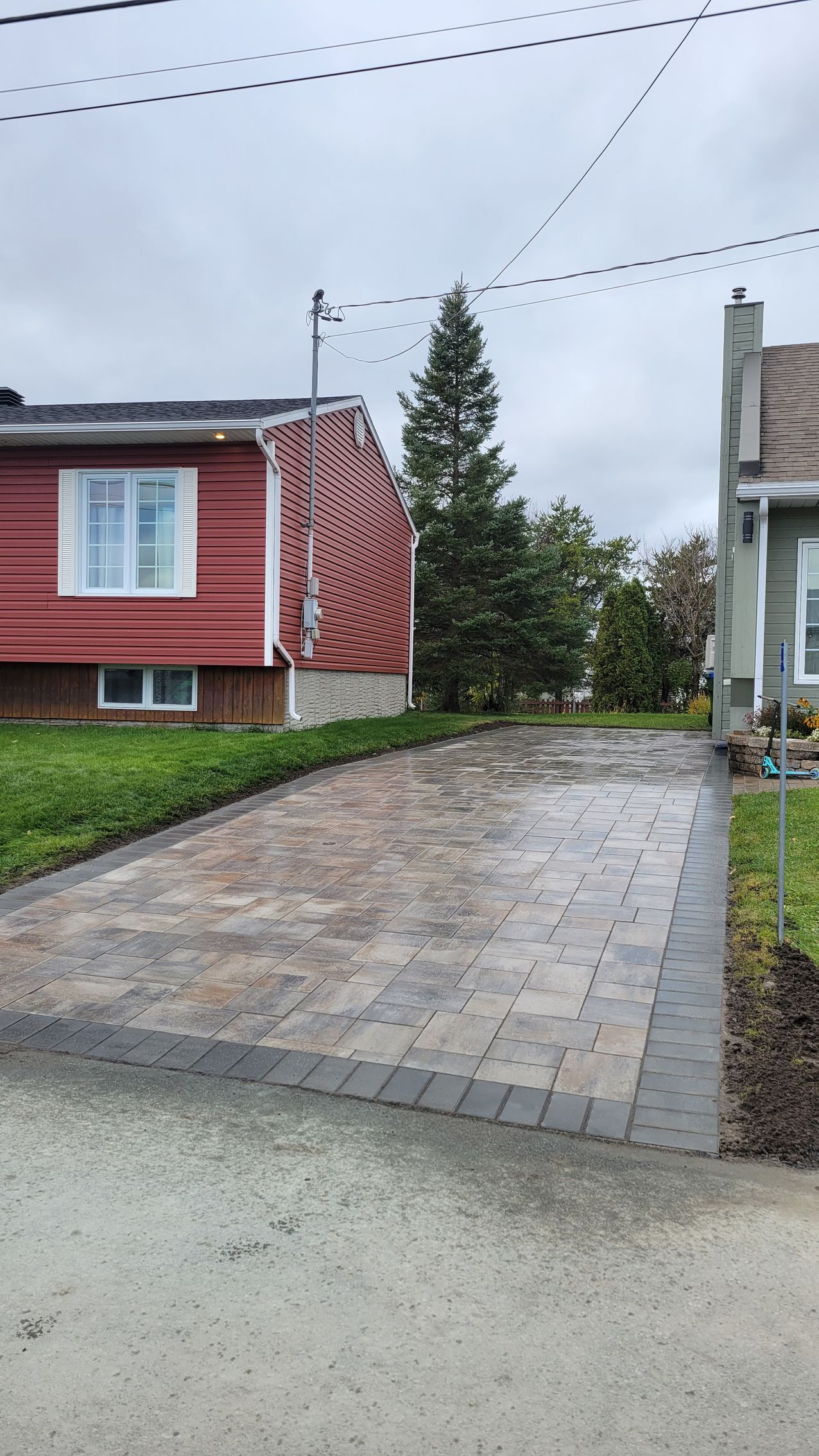 Une allée est en cours de construction devant une maison rouge.