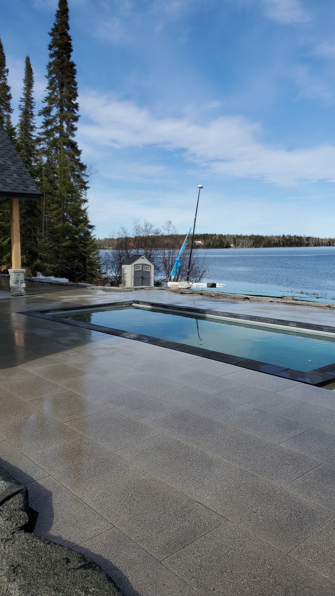 Vue sur le lac, avec une étendue d'eau calme, un ciel bleu et une terrasse avec un bassin réfléchissant.
