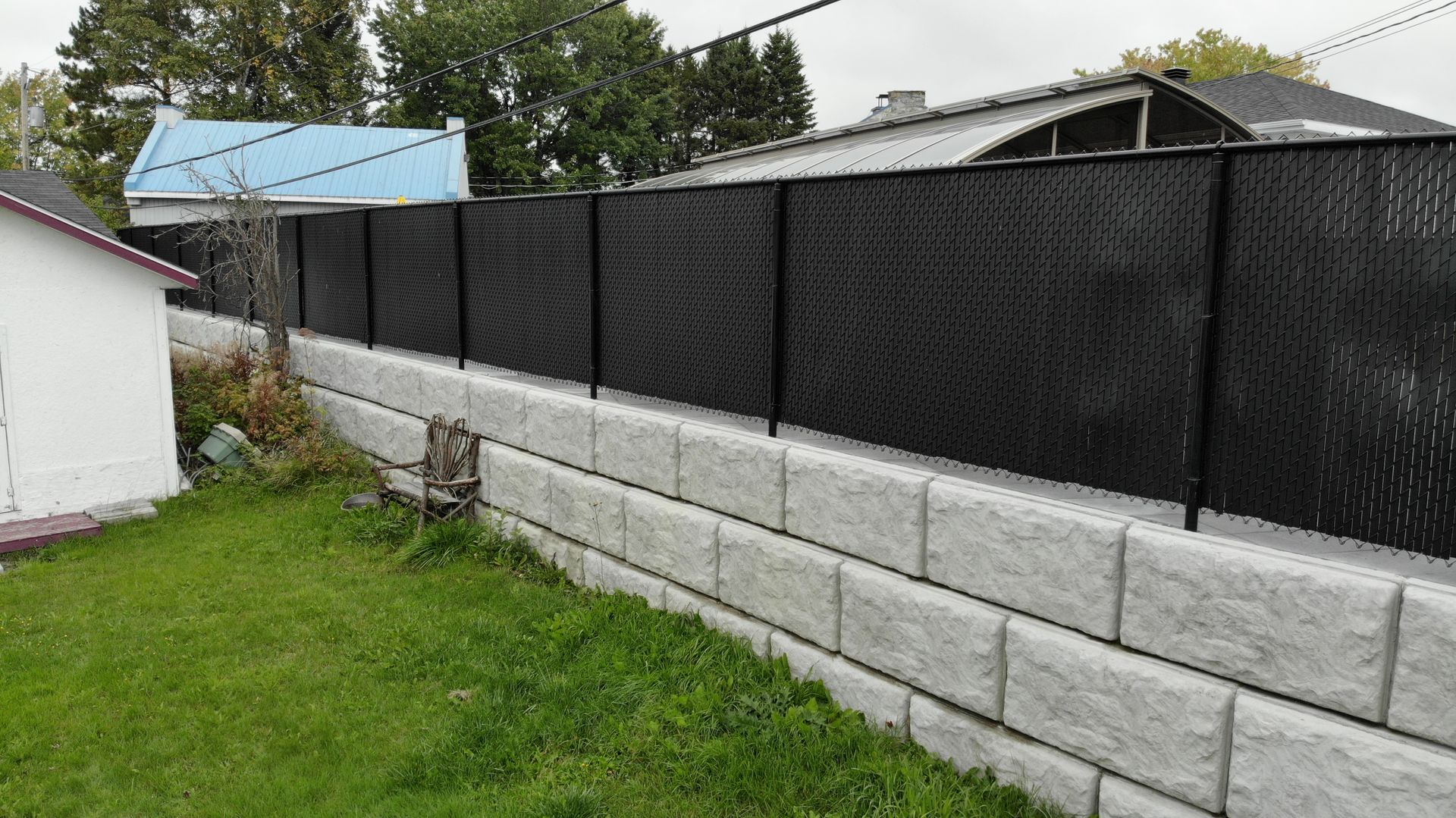 Une clôture noire entoure un mur de briques dans une cour arrière.