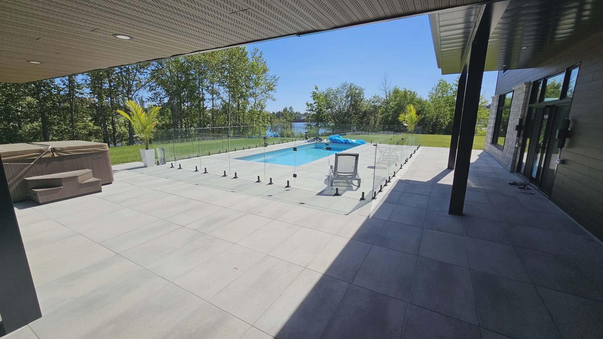 Vue sur le lac, avec une étendue d'eau calme, un ciel bleu et une terrasse avec un bassin réfléchissant.