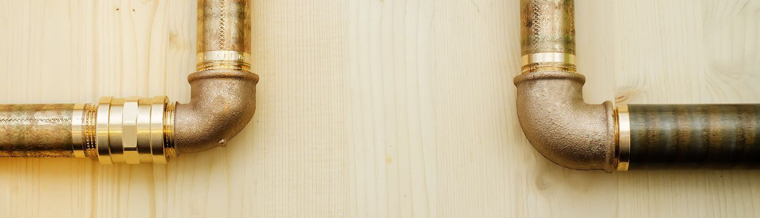 Two pipes are connected to each other on a wooden wall.