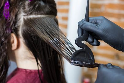 A woman is getting her hair dyed by a hairdresser.